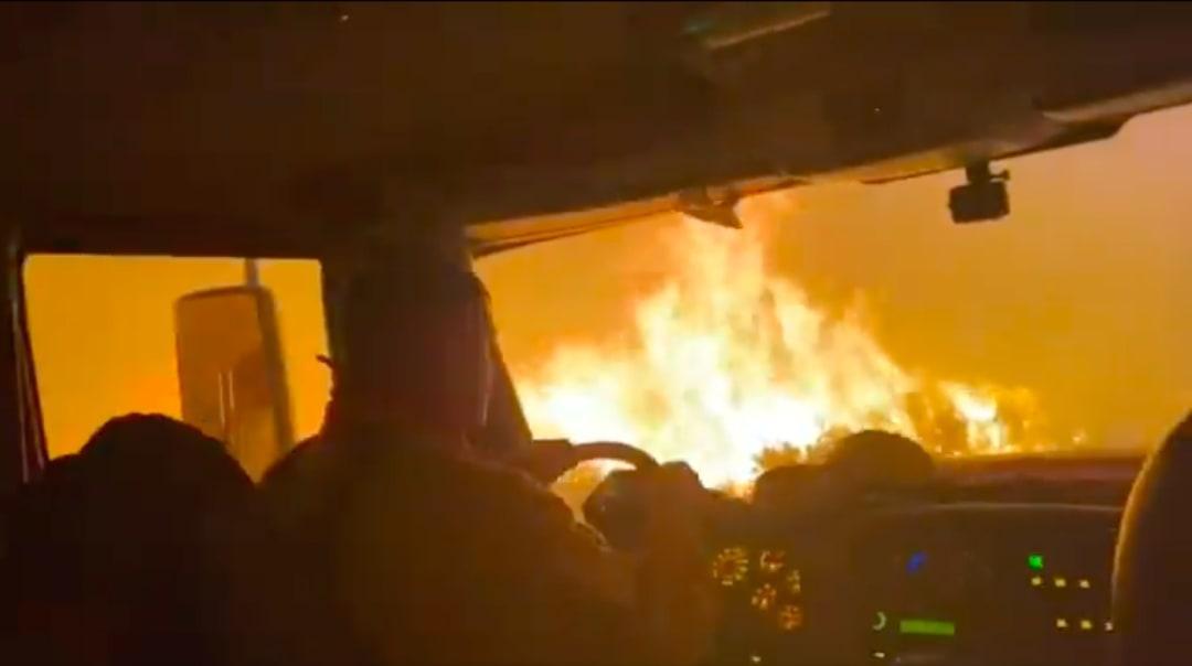 Firefighters drive truck amid tall flames of US wildfire; video